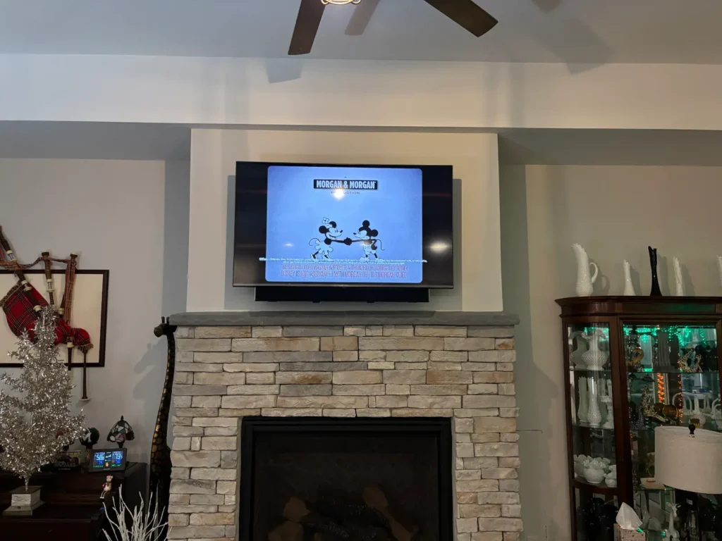 TV mounted above stone fireplace with pull down mount in Shores Florida