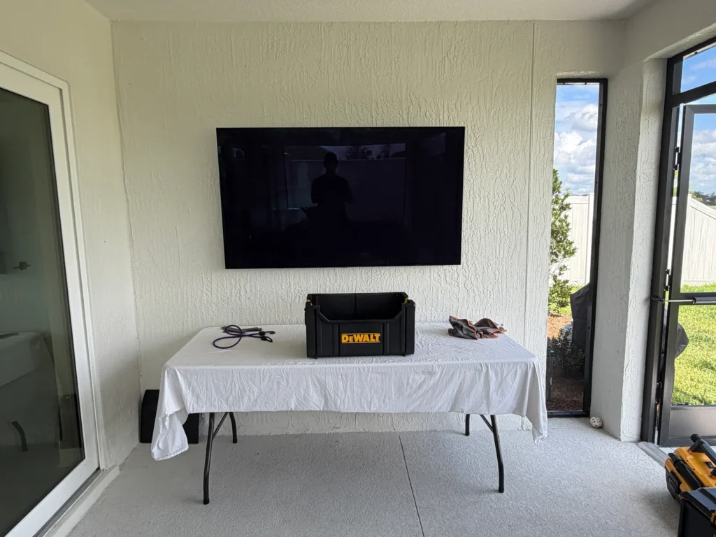 65-inch outdoor TV professionally mounted on a full-motion wall mount in a screened lanai in Ocala, Florida.