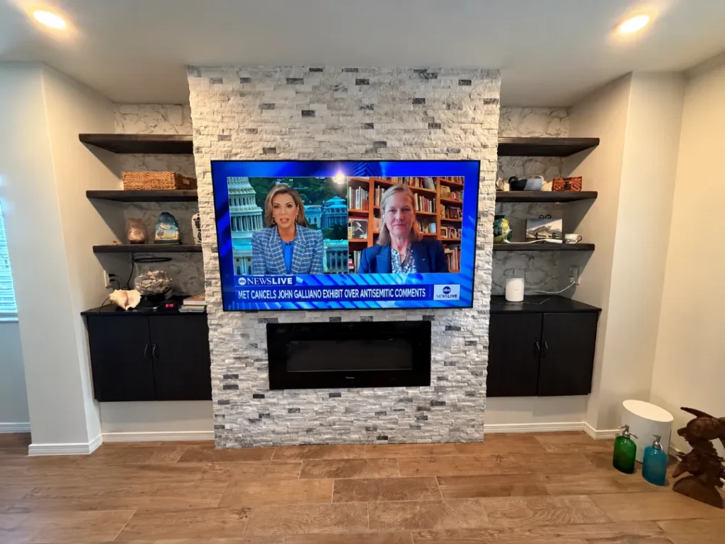 70-inch TV mounted above stone fireplace using a custom-built support frame and flat tilt TV mount in Ocala Florida