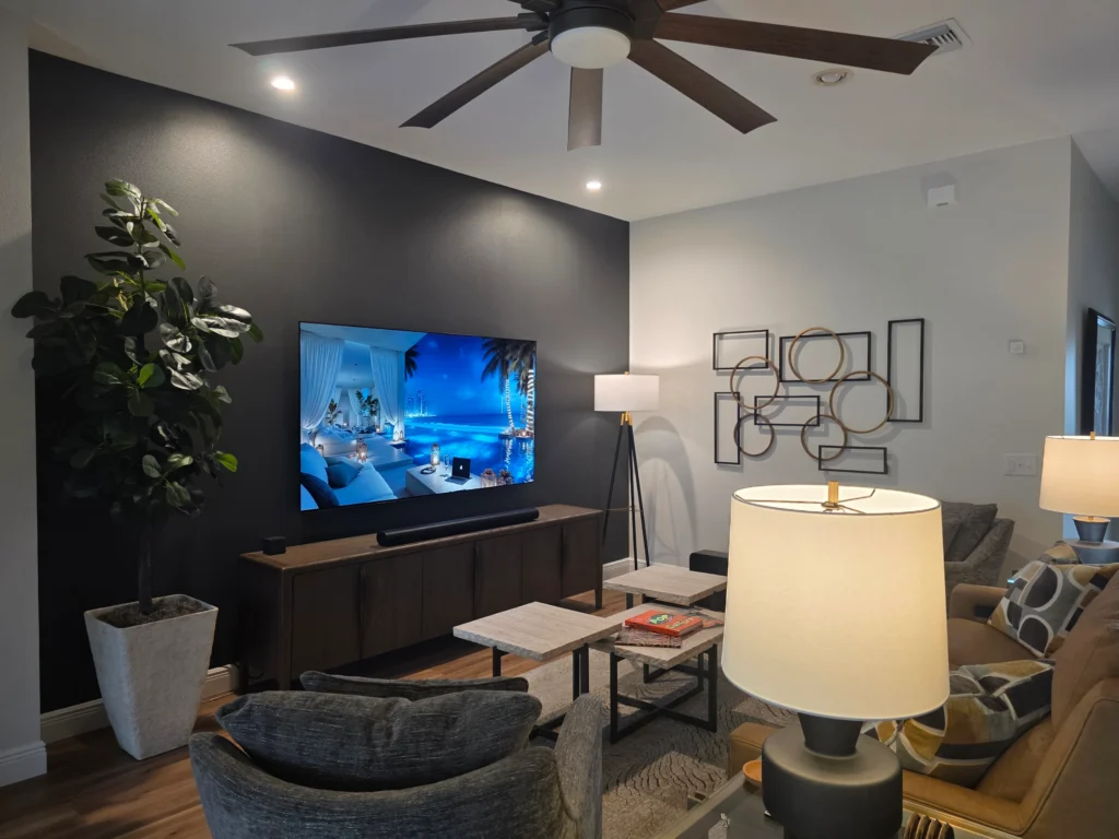 83-inch TV mounted with in-wall power bridge, Sonos surround sound setup, mirror installation, and large wall art installation in The Villages Florida