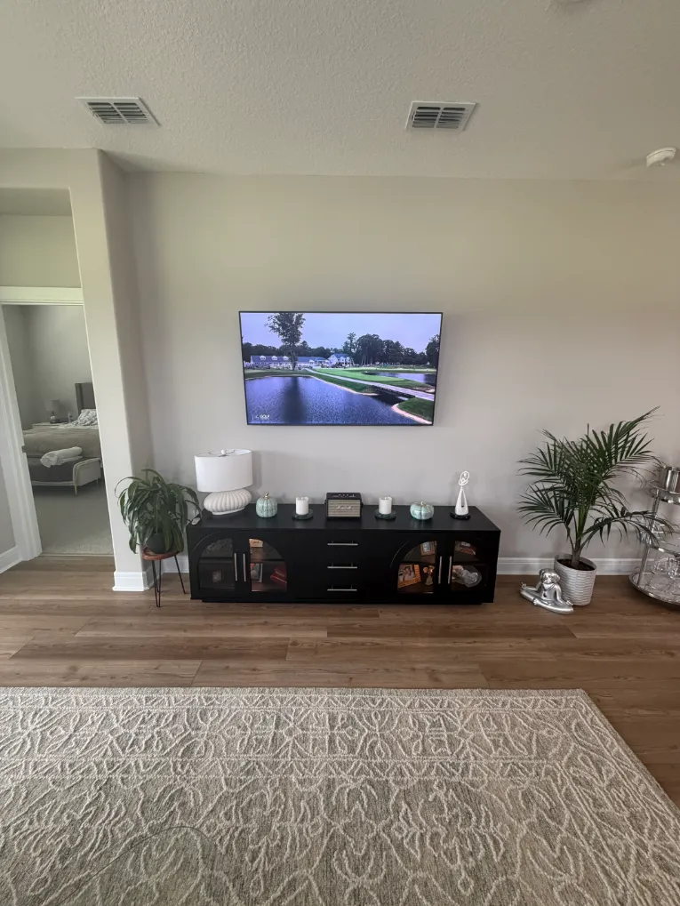 Finished black TV console cabinet professionally assembled below wall-mounted TV in Ocala Florida